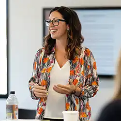 A founder stands facing towards the camera while she addresses her off-camera team.